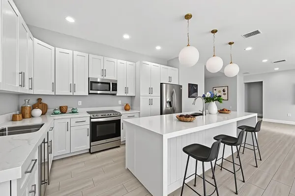 a kitchen with a sink a stove a refrigerator and chairs