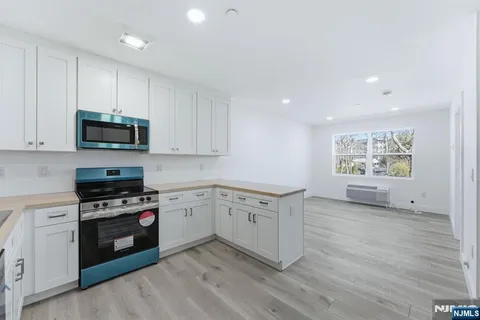 a kitchen with granite countertop a stove top oven cabinets and a wooden floor