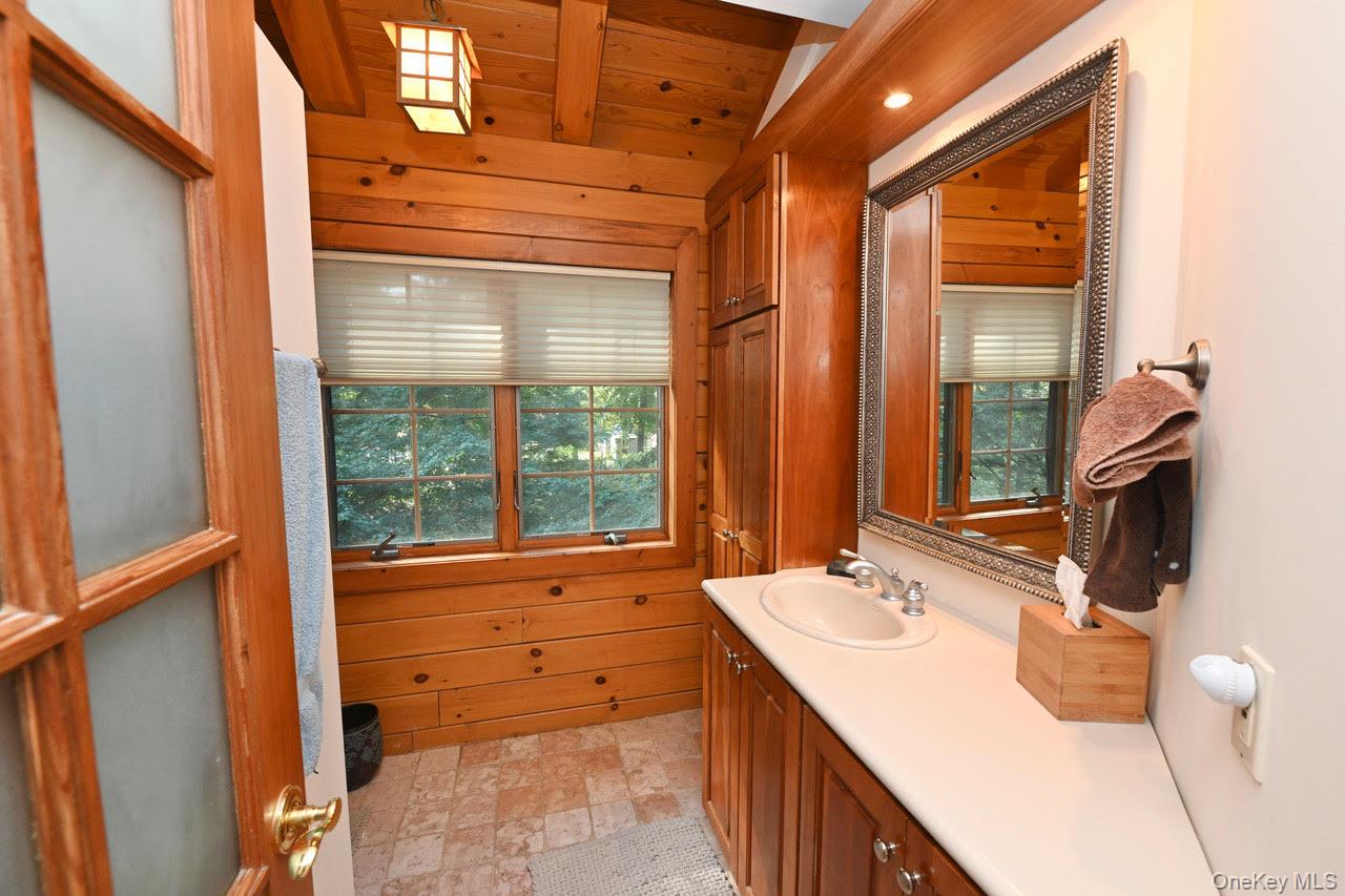 216 5th Street St. James, NY 11780 - Photo 15 of 21 Bathroom with vanity, healthy amount of natural light, wooden walls, and wood ceiling