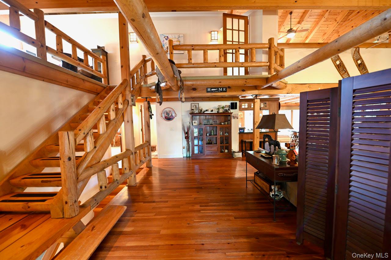 216 5th Street St. James, NY 11780 - Photo 10 of 21 Staircase featuring hardwood / wood-style flooring, a high ceiling, and a ceiling fan