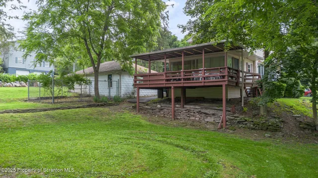 a backyard of a house with wooden deck and outdoor seating
