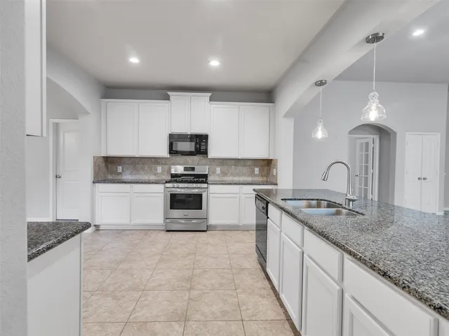 a large kitchen with granite countertop a stove sink and cabinets