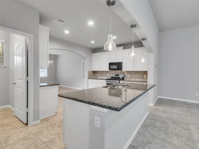 a kitchen with kitchen island granite countertop a sink a counter and stainless steel appliances