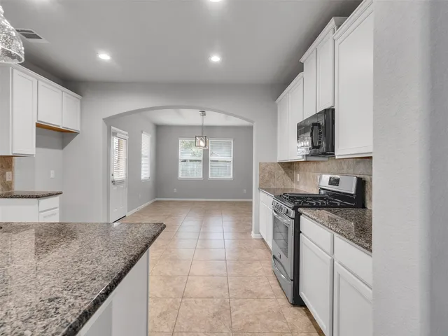 a kitchen with stainless steel appliances granite countertop a stove a sink and a microwave