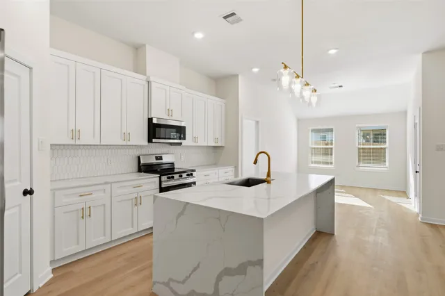 a kitchen with stainless steel appliances granite countertop a sink dishwasher and a stove with wooden floor