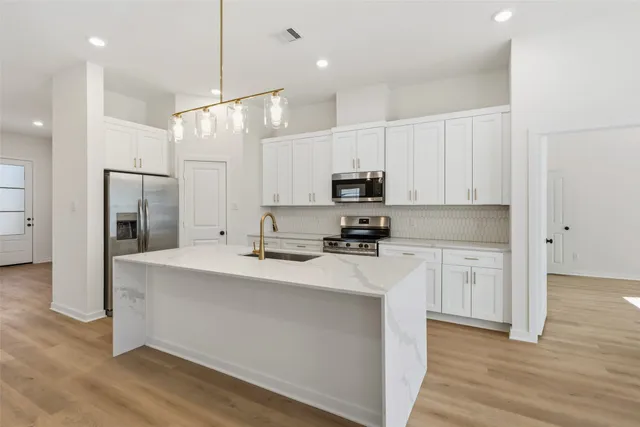 a kitchen with kitchen island white cabinets and stainless steel appliances