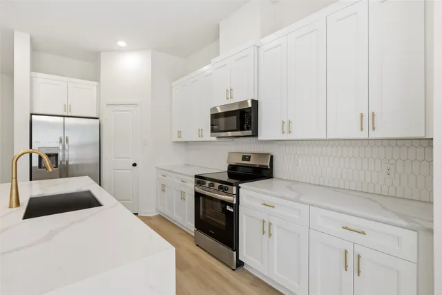 a kitchen with white cabinets and stainless steel appliances
