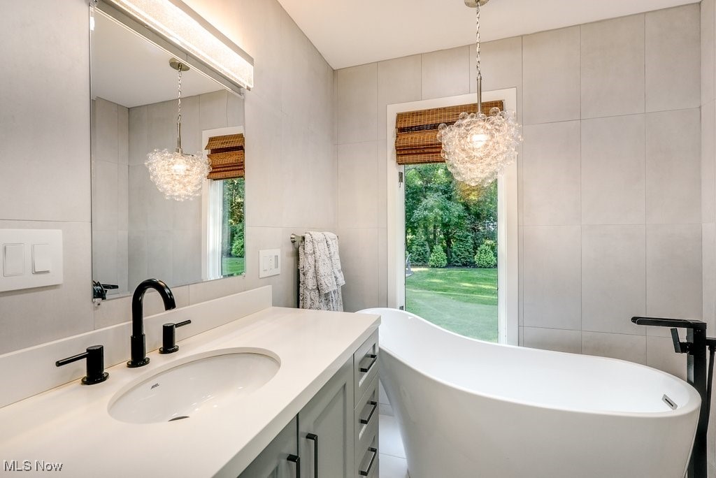 1598 Graham Road Silver Lake, OH 44224 - Photo 30 of 46 Bathroom with vanity, tile walls, a bathtub, tile patterned floors, and a chandelier