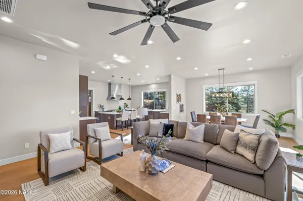 a kitchen with stainless steel appliances granite countertop a stove top oven a sink dishwasher a dining table and chairs with wooden floor