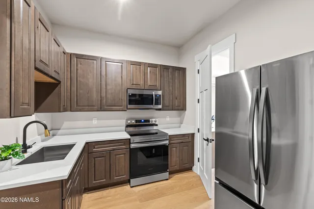 a kitchen with stainless steel appliances granite countertop a stove top oven a sink dishwasher a dining table and chairs with wooden floor