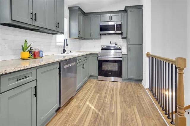 a kitchen with stainless steel appliances granite countertop a sink dishwasher stove top oven and refrigerator with wooden floor