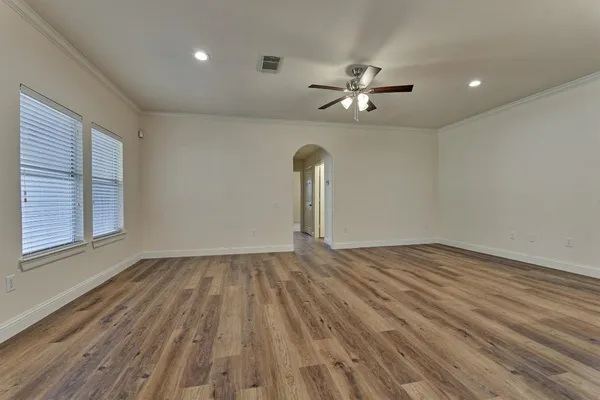 a view of an empty room with window and wooden floor