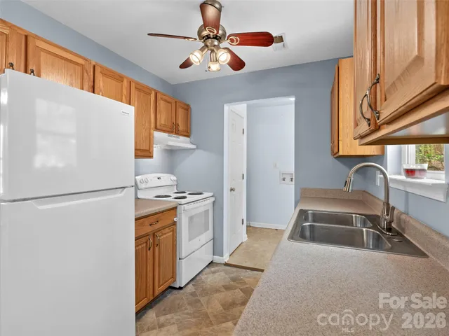 a kitchen with stainless steel appliances granite countertop a refrigerator a stove a sink a dining table and chairs with wooden floor