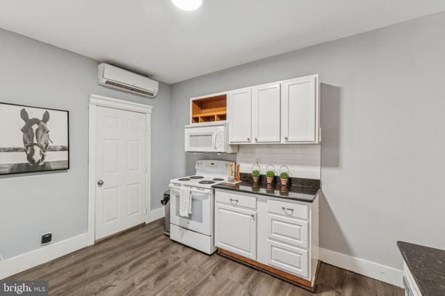 a kitchen with white cabinets and wooden floor