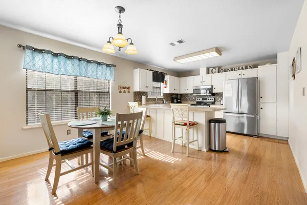 a kitchen with stainless steel appliances kitchen island granite countertop a table chairs and a refrigerator