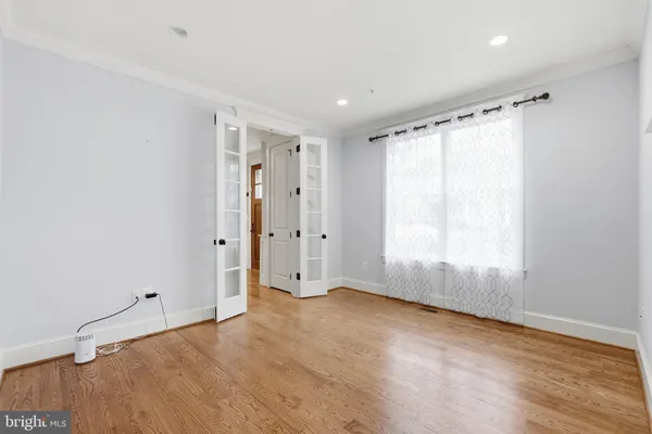 a view of an empty room with wooden floor and a window