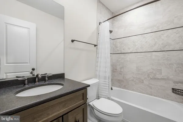a bathroom with a granite countertop sink toilet a mirror and shower