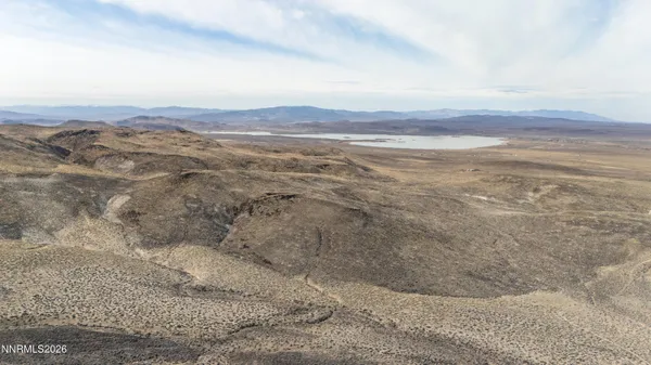 a view of a dry field with mountains in the background