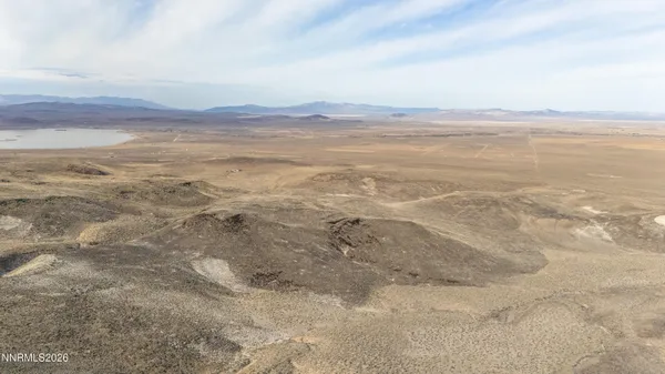 a view of a dry field with mountains in the background