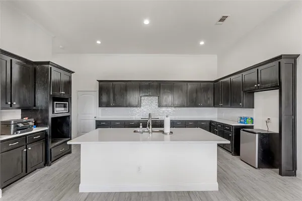 a large kitchen with stainless steel appliances a large counter top a stove and a refrigerator