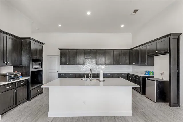 a large kitchen with stainless steel appliances a large counter top a stove and a refrigerator