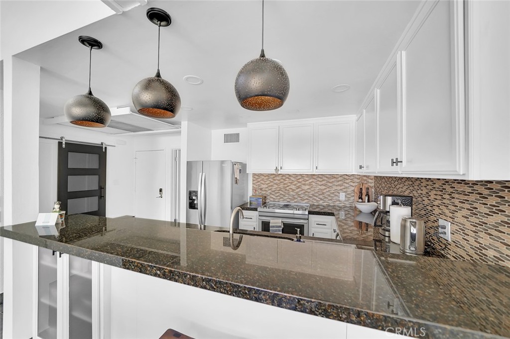 6301 Marina Pacifica Drive Long Beach, CA 90803 - Photo 6 of 39 a kitchen with stainless steel appliances granite countertop a sink a counter space and cabinets