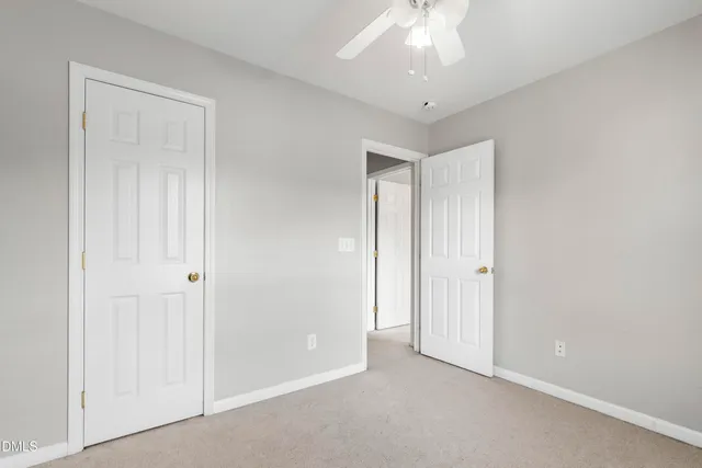 a view of an empty room and chandelier fan