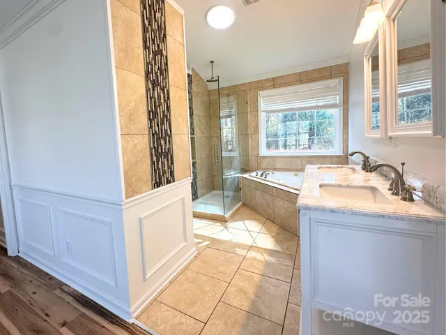 a spacious bathroom with a tub sink and mirror