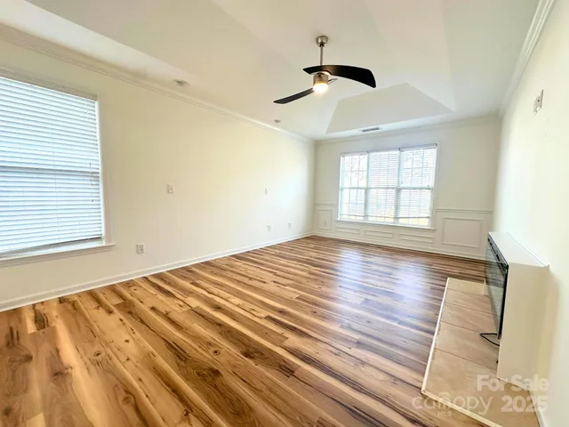 a view of empty room with wooden floor and fan
