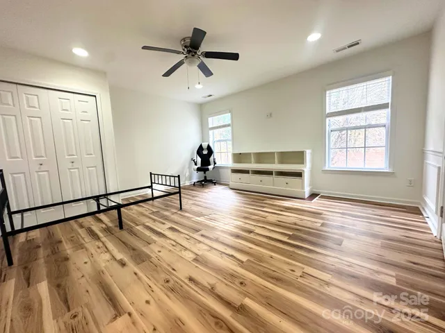 an empty room with wooden floor cabinet and windows