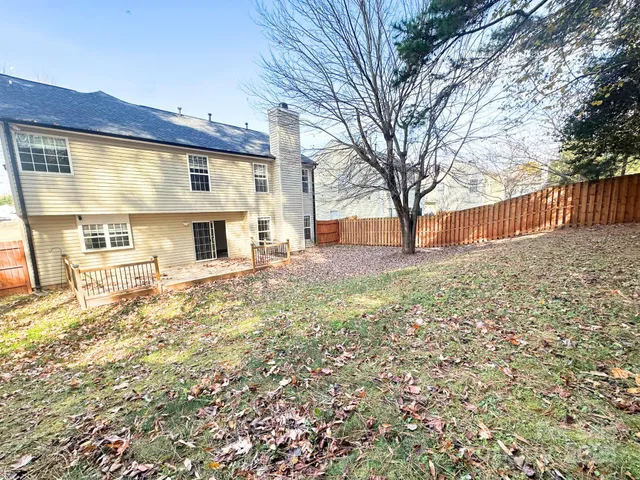 a backyard of a house with large trees and outdoor seating