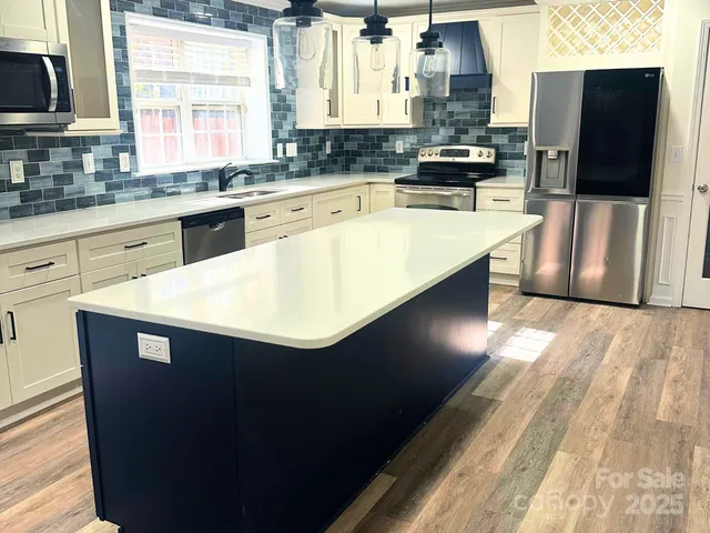 a kitchen with stainless steel appliances granite countertop a sink a stove and a refrigerator