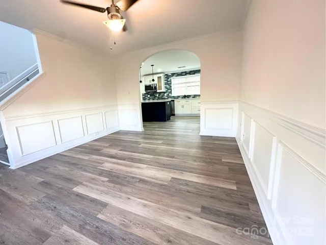 a view of a hallway with wooden floor windows and a kitchen