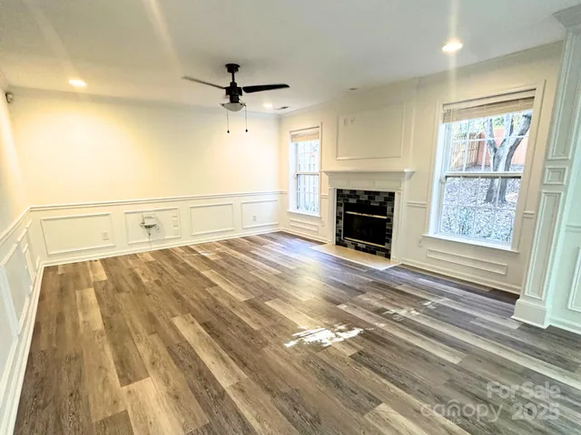 a view of a livingroom with a fireplace a ceiling fan and windows