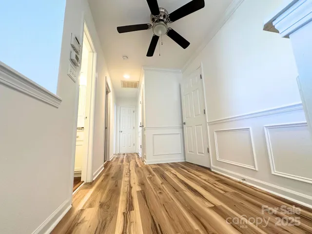 a view of a bedroom with wooden floor and a ceiling fan