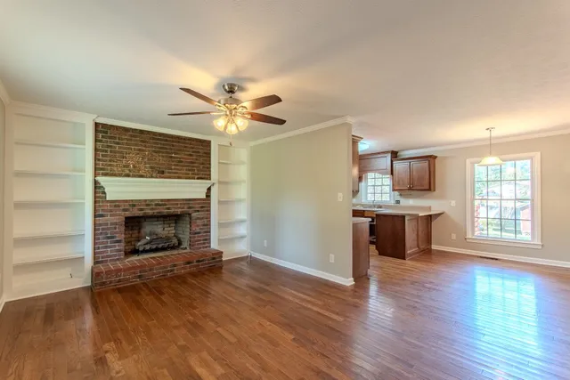 an empty room with a fireplace and wooden floor
