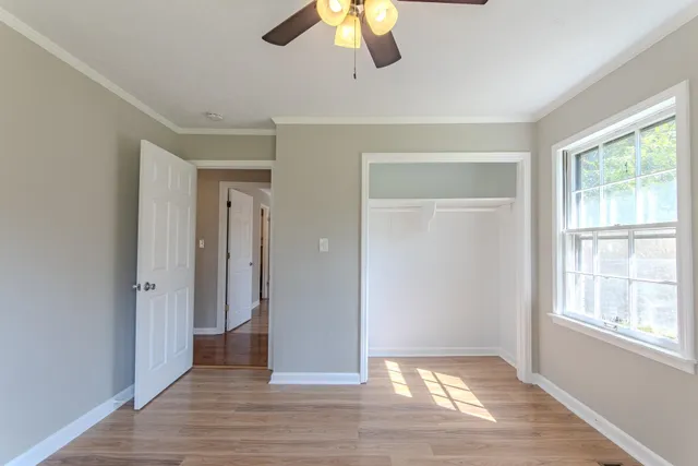 a view of an empty room with wooden floor and window
