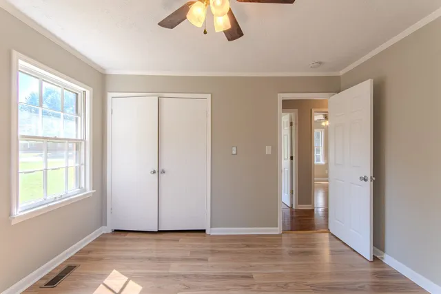 a view of an empty room with wooden floor and a window