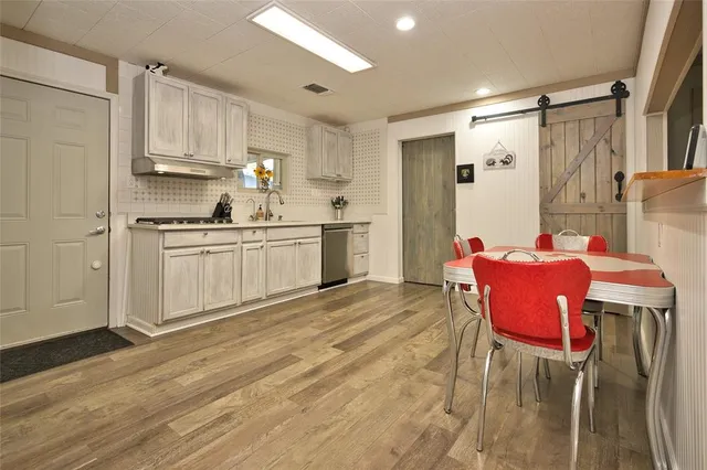 a kitchen with stainless steel appliances granite countertop a dining table chairs and granite counter tops