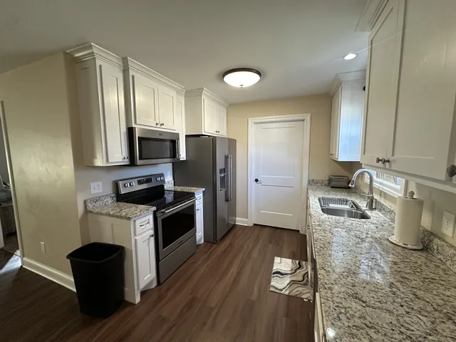 a kitchen with a sink wooden floor and stainless steel appliances