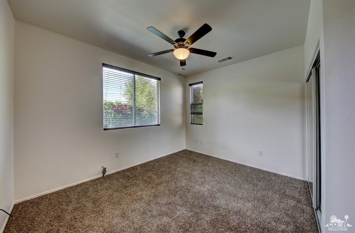 83275 Lightning Road Indio, CA 92203 - Photo 21 of 28 an empty room with window and ceiling fan