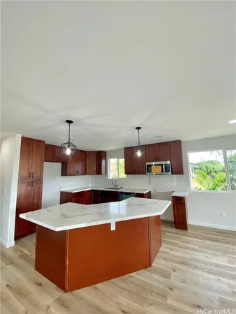 a large kitchen with stainless steel appliances a large counter top a stove and a wooden floors