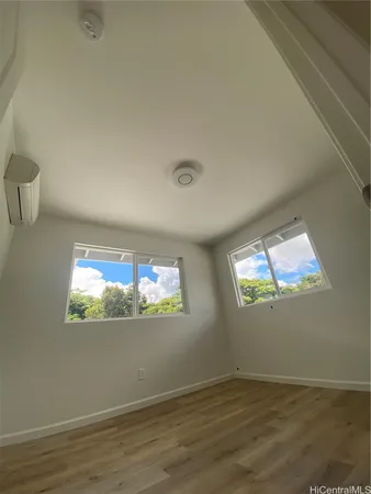 an empty room with wooden floor a chandelier and windows