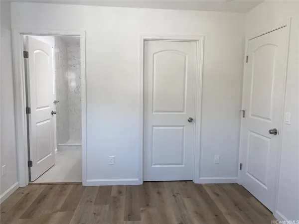 an empty room with wooden floor and closet area