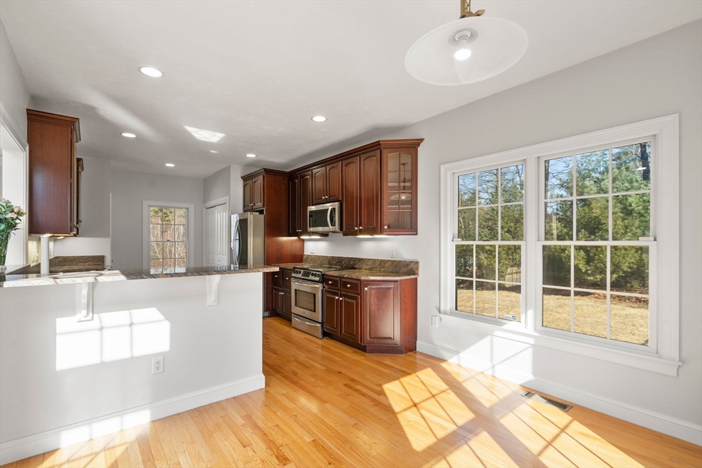 40 Sandy Ridge Road Sterling, MA 01564 - Photo 11 of 33 a large kitchen with stainless steel appliances granite countertop a large stove top oven a sink dishwasher a dining table and chairs with wooden floor