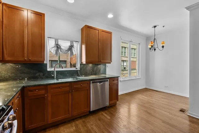 a kitchen with stainless steel appliances granite countertop wooden cabinets a sink and dishwasher with wooden floor