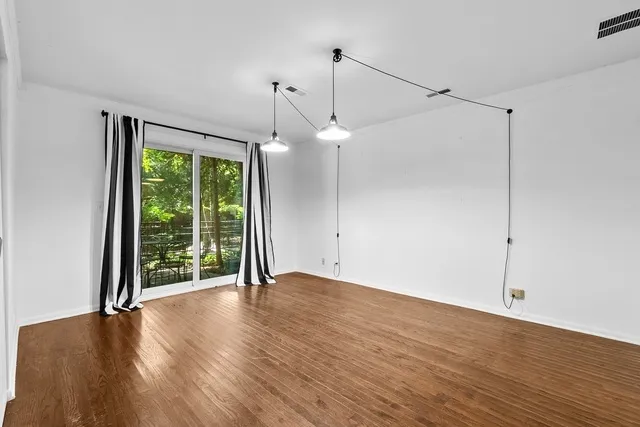 a view of an empty room with wooden floor fridge and a window