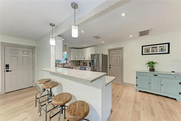 a open kitchen with stainless steel appliances granite countertop a stove a sink a dining table and chairs with wooden floor