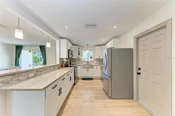 a large white kitchen with cabinets a sink and stainless steel appliances