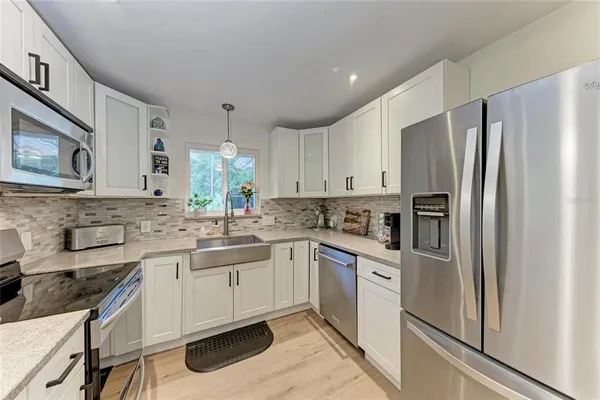 a kitchen with white cabinets stainless steel appliances and a window